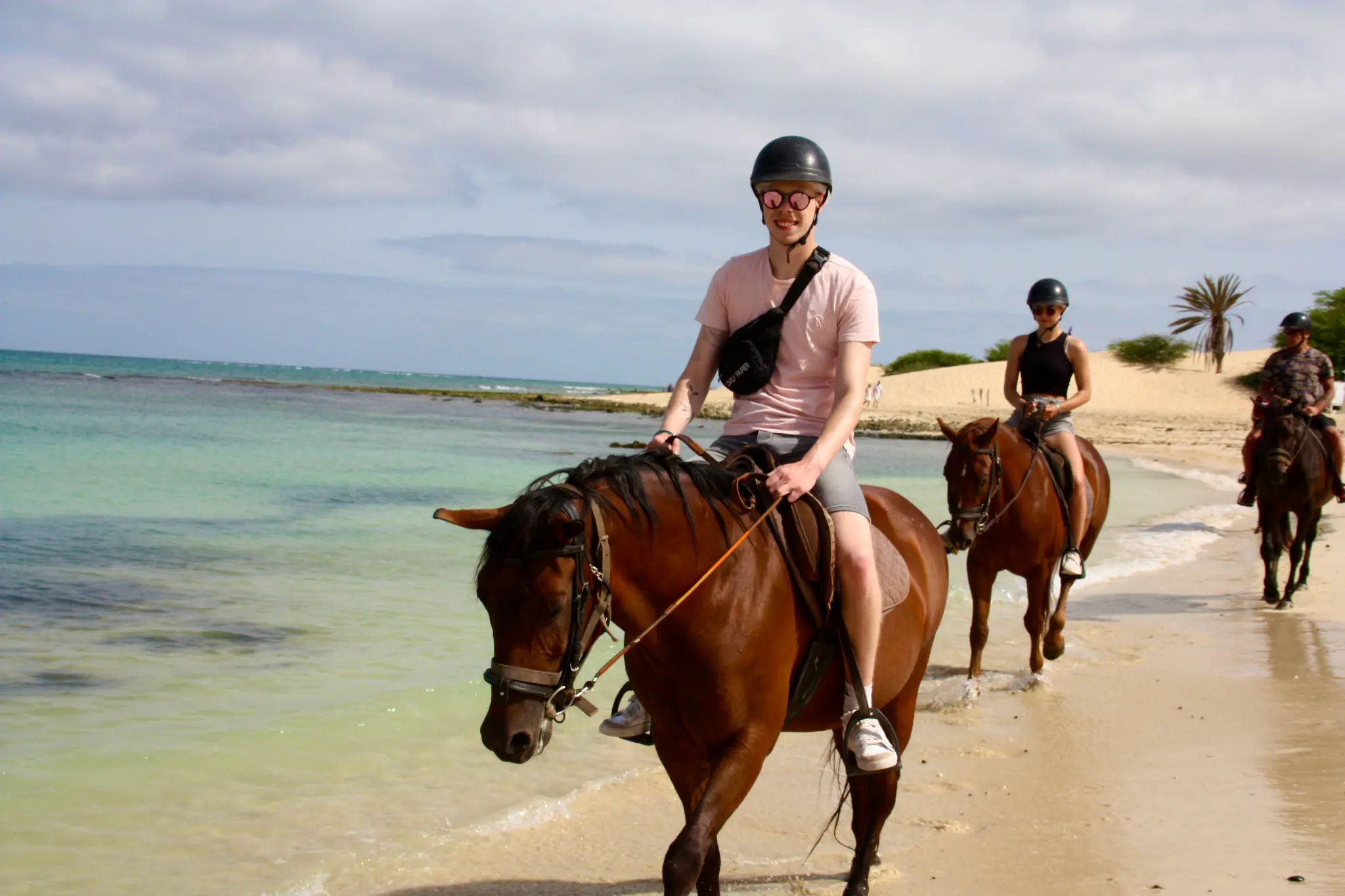 A small riding group travelling along the shoreline