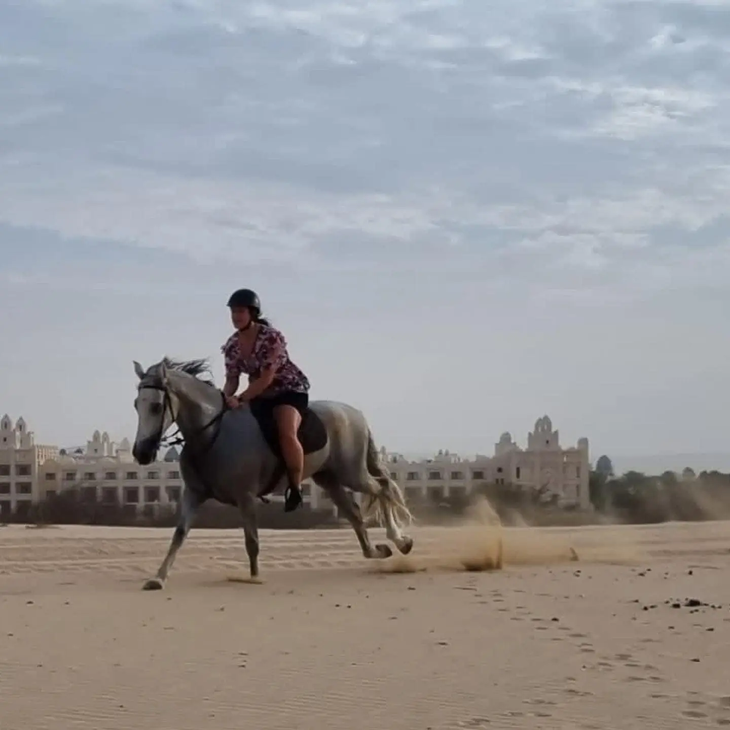 Horse and rider galloping across the sand near Riu Palace